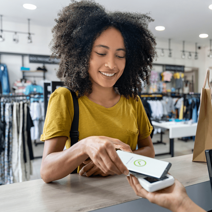 Happy customer paying with a mobile phone in a fashion store.