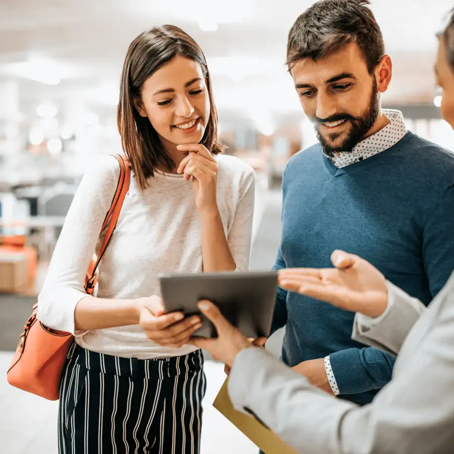 A couple being assisted by an associate in a store using a mobile device.